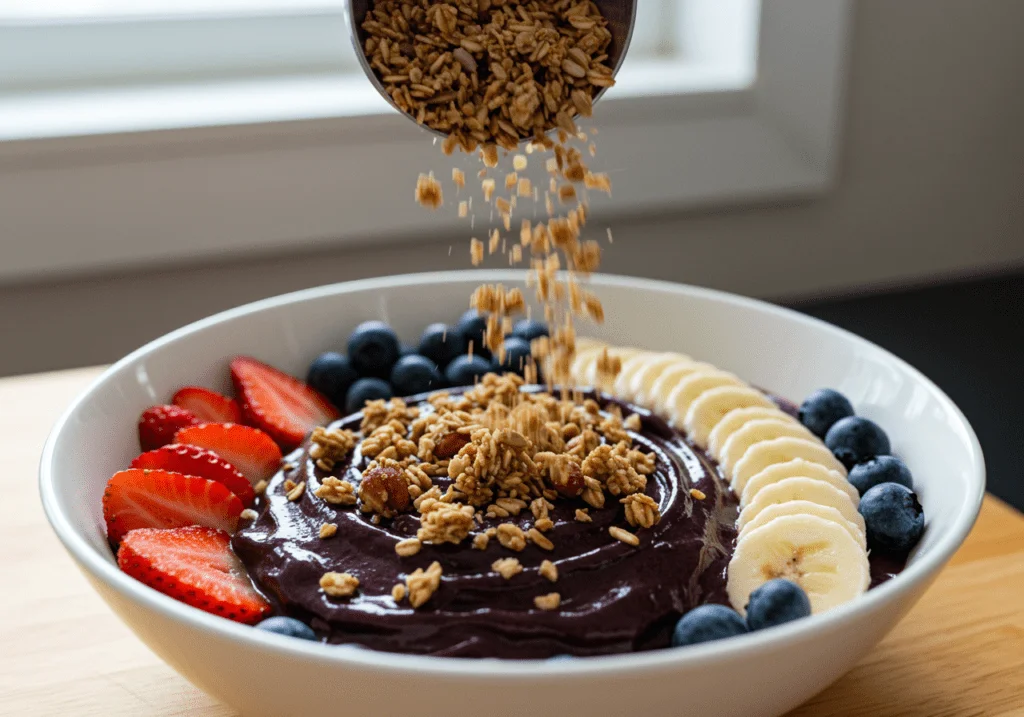 Granola caseira sendo adicionada à tigela de açaí na receita Energizante do Norte.